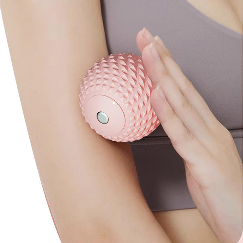 A girl is using a pink spiky massage ball to massage her forearm