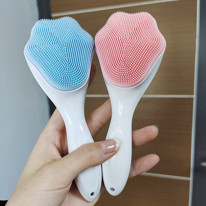 A hand holding blue and pink handheld silicone face scrubber exfoliators